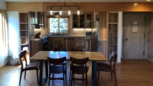 A modern kitchen with wooden cabinets, a central island, and a hanging light fixture. - Mammoth Creek Unit 12 (Mammoth Lakes)