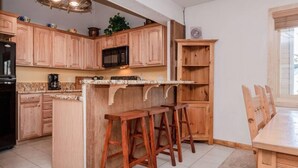 Una cucina con mobili in legno, un forno a microonde, una macchina da caffè e un'area con uno sgabello da bar.