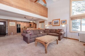 Ein geräumiges Wohnzimmer mit hohen Decken, einem Holztisch und einem großen Fenster.