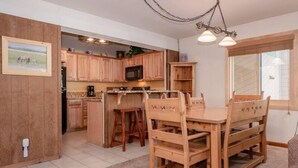 Una cucina con mobili in legno, un tavolo da pranzo con sedie e un lampadario.