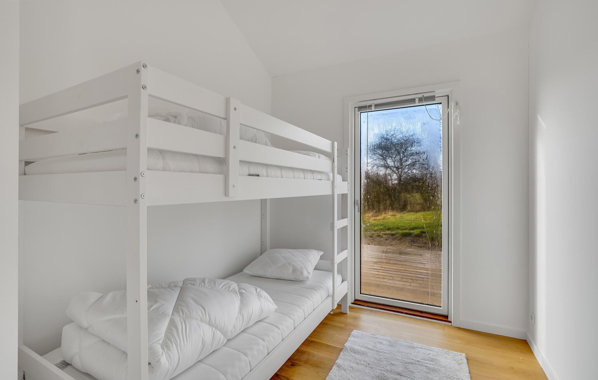 A bunk bed room with a sliding glass door leading to an outdoor area.