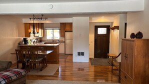 Una cocina compacta con armarios de madera, una isla central y una zona de comedor con sofá y sillas a cuadros.