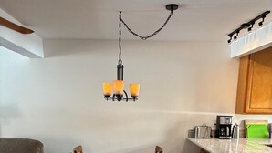 Un comedor con una mesa de madera, sillas y una araña.