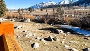 A wooden bench overlooking a mountainous landscape with a clear sky. - Mammoth Creek Unit 32 (Mammoth Lakes)