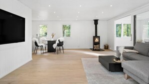 A modern living room with a fireplace, a dining area, and a sofa. - Nice home in Farsø with house a panoramic view (Farsø)