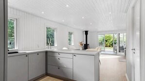 A modern kitchen with white cabinetry, a central island, and a black stove. - Nice home in Farsø with house a panoramic view (Farsø)