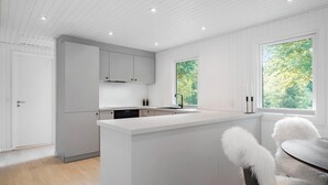 A modern kitchen with white cabinetry, a central island, and a window with a view of greenery. - Nice home in Farsø with house a panoramic view (Farsø)