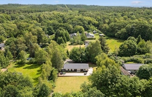 An aerial view of a residential area with multiple houses surrounded by dense forest.
