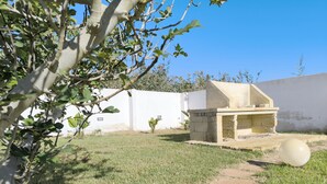 A courtyard with a stone structure, a white wall, and a tree. - La Torre by Interhome (Ugento)
