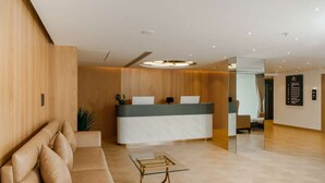 Et moderne receptionsområde med en træreception, en sofa og et sofabord i glas.