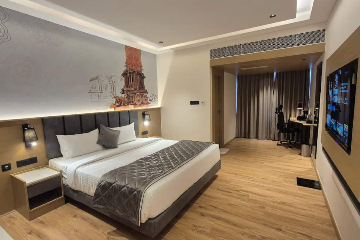 Una habitación de hotel moderna con una cama grande, un escritorio y una televisión.