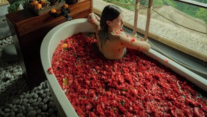 A bathtub filled with red flowers, a wooden bench with a basket of fruits and a plant, and a view of lush greenery through a window. - Marangga ubud valley view & private pool (Ubud)