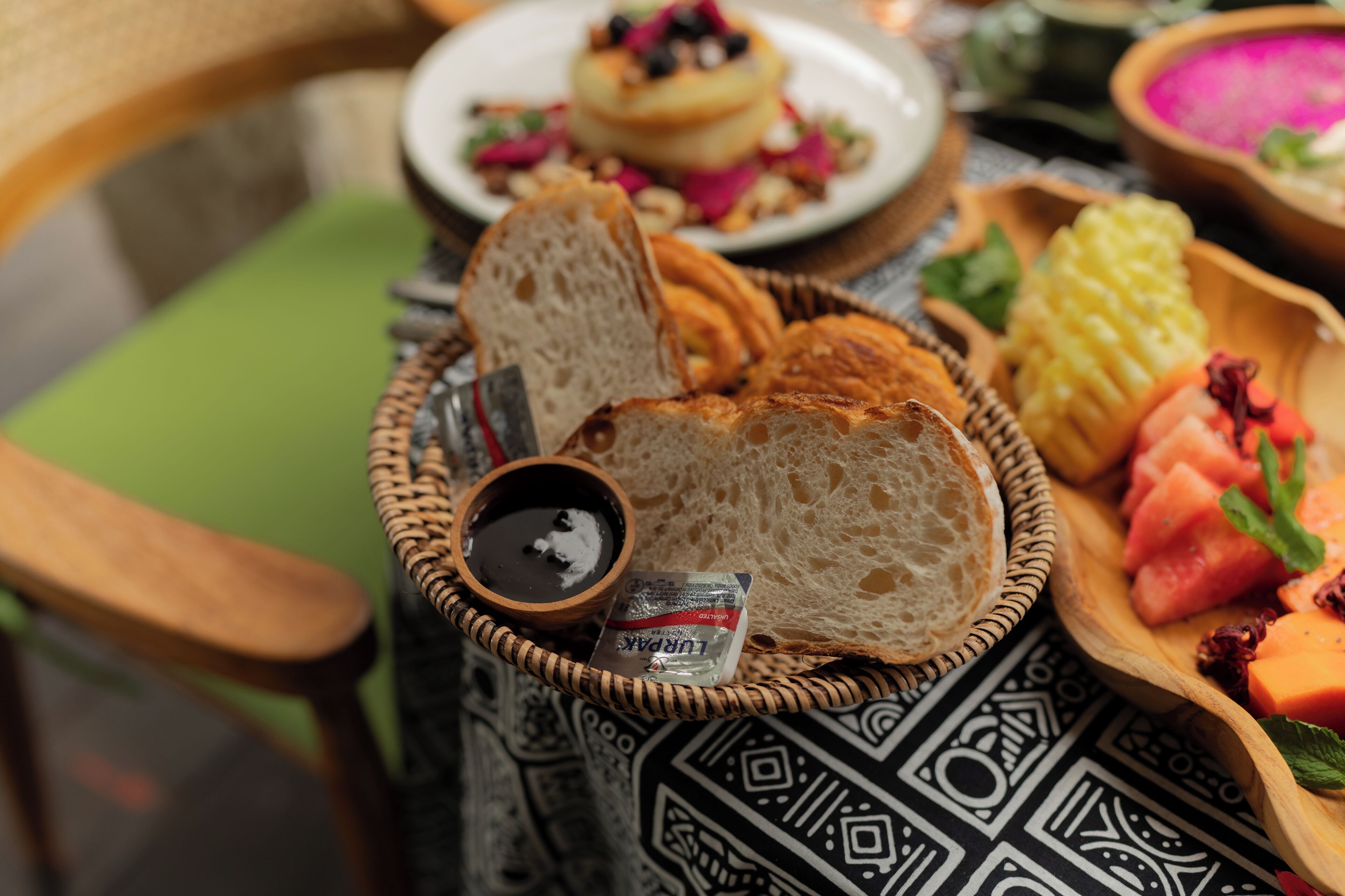 A breakfast setting with bread, a bowl of fruit, and a cup of coffee on a table.