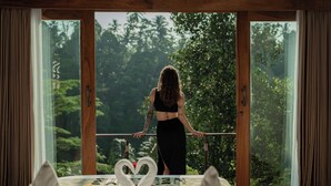 A room with a large window, a heart-shaped decoration on the table, and a person standing by the window. - Marangga ubud valley view & private pool (Ubud)