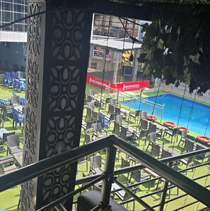 A poolside area with chairs and tables, a pool, and a stage with a banner. - Wellington Hotels Limited  (Warri)