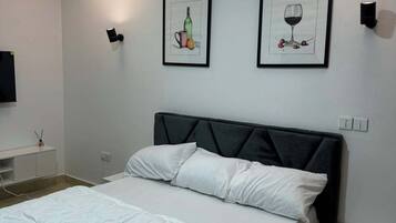 A modern bedroom with a large bed, a bedside table, a nightstand, and two wall-mounted light fixtures.