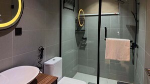 A modern bathroom with a glass-enclosed shower, a round mirror, and a white sink. - Wellington Hotels Limited  (Warri)