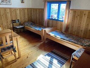 A wooden room with a bed, a chair, and a table. - Off Grid at Fjätälven (Sarna)