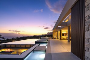 Eine moderne Lounge-Bereich im Freien mit einem Feuerbereich, einer Steinsäule und Blick auf die Landschaft.
