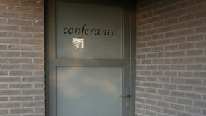 A conference room door with the word "conference" on it, set in a brick wall. - Countryside holiday home (Gijverinkhove)