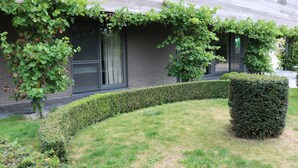 A building with a brick facade, a neatly trimmed hedge, and a well-maintained lawn. - Countryside holiday home (Gijverinkhove)