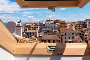 Blick von einem Holzbalkon auf dicht bebautes Stadtgebiet mit traditioneller Architektur und blauem Himmel.