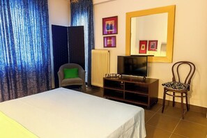 A hotel room with a bed, a TV on a wooden stand, a chair, and a large mirror on the wall. - Verdant Escape Corfu (Corfu)