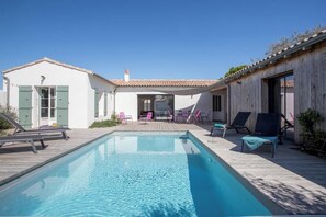 Ein rechteckiger Swimmingpool mit Liegestühlen und einer Holzterrasse.