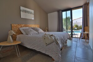 A bedroom with a bed, a bedside table, a lamp, a large window, and a view of the outdoors. - 300 metres from beach & restaurants, a brand new modern villa with heated pool (La Couarde-sur-Mer)