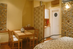 A room with a bed, a wooden dining table with chairs, a small kitchenette, and a wardrobe. - Spianada Dimora Corfu (Corfu)
