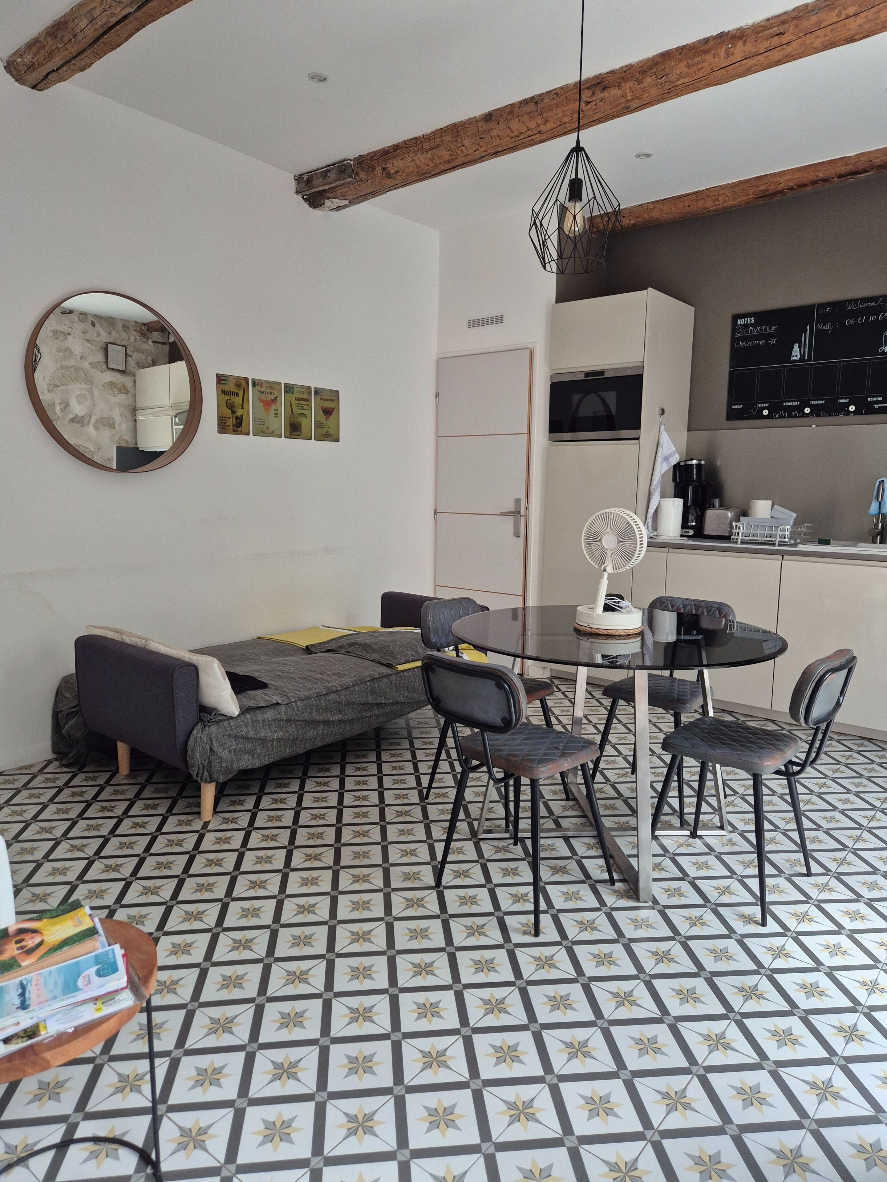 Ein zeitgemäßer Wohnbereich mit Sofa, Esstisch, Stühlen und einer Küchenzeile mit einer Kreidetafel-Speisekarte.