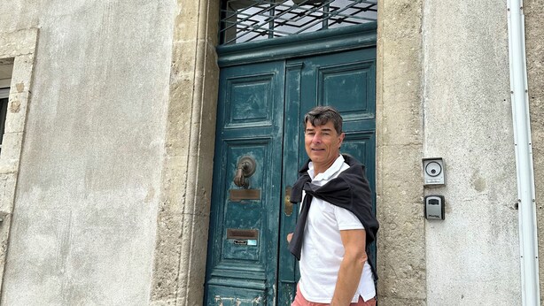 A man standing in front of a weathered green door with a metal latch and a small plate above it. - Charming 3★ Holiday Home — Historic Heart of Béziers, Peaceful Courtyard, Secret (Béziers)
