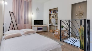 A bedroom with a bed, bedside table, bookshelf, and a TV. - Charming 3★ Holiday Home — Historic Heart of Béziers, Peaceful Courtyard, Secret (Béziers)