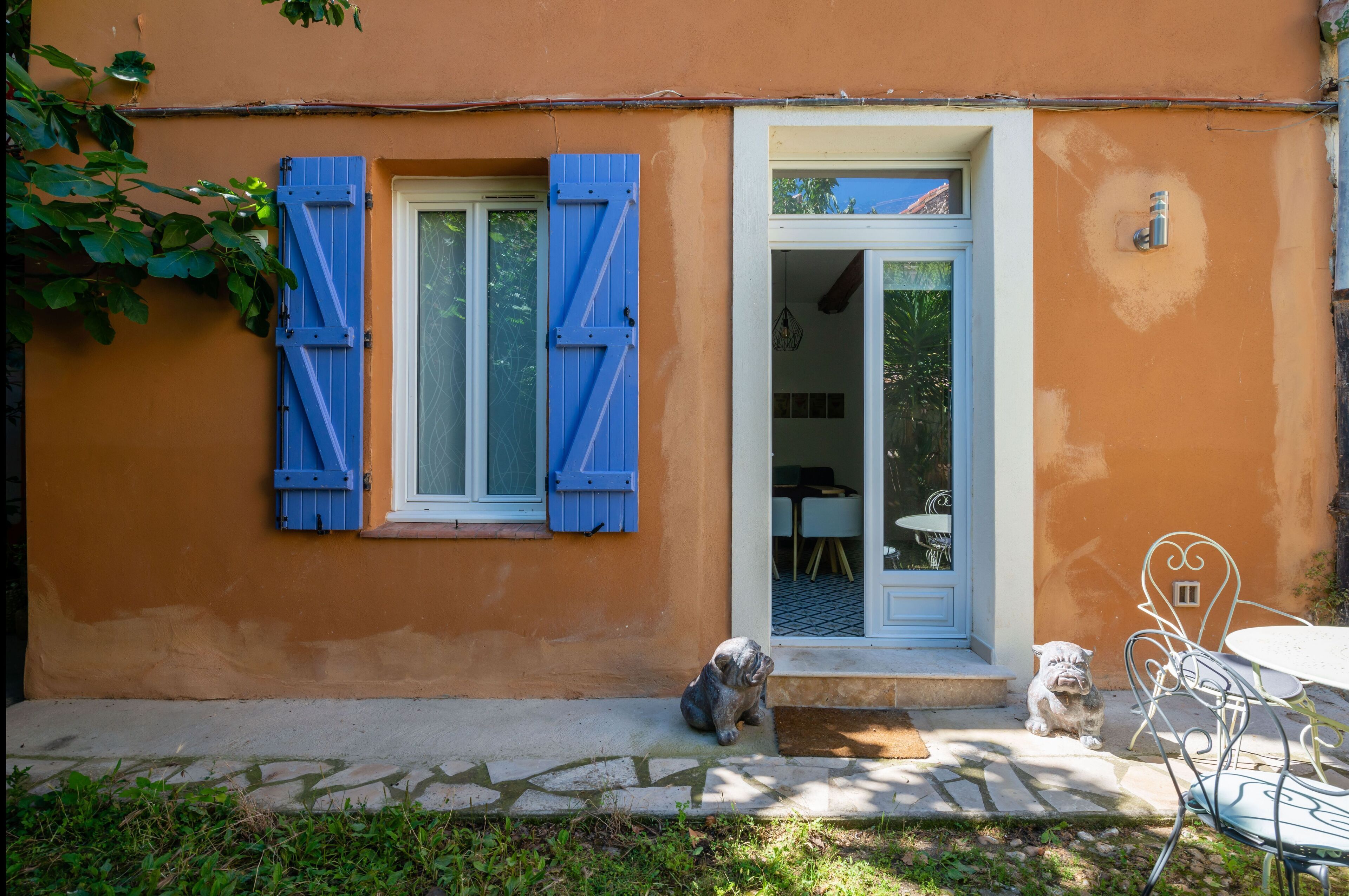 A building with orange walls, blue shutters, and a white door.