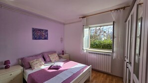 Een slaapkamer met een bed, nachtkastjes, een raam met gordijnen en een radiator.