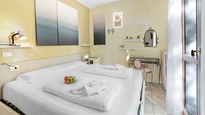 Habitación de hotel con una cama grande, mesitas de noche, un escritorio con silla, un espejo y obras de arte en las paredes.