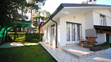 A modern house with a patio, a covered outdoor seating area, and a well-maintained garden.