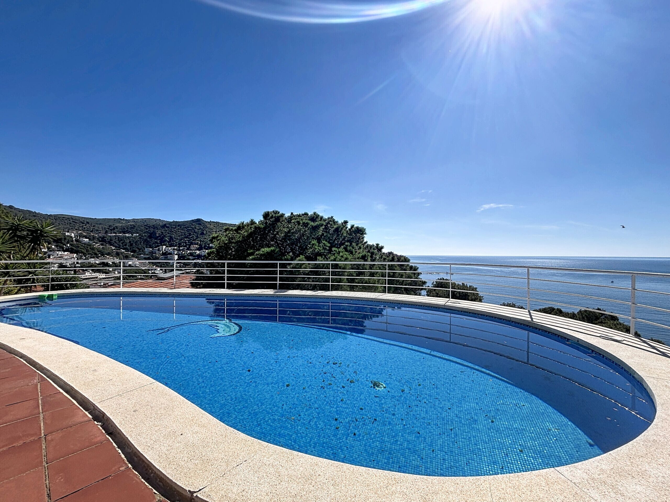 A swimming pool with a clear view of the sea and hills in the background.