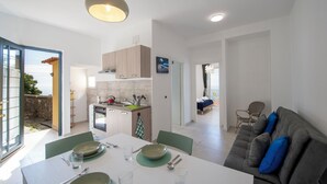 A modern kitchen with a dining area, a sofa, and a view of the outdoors. - VivimiHome - Casa Angelina (Conca dei Marini)