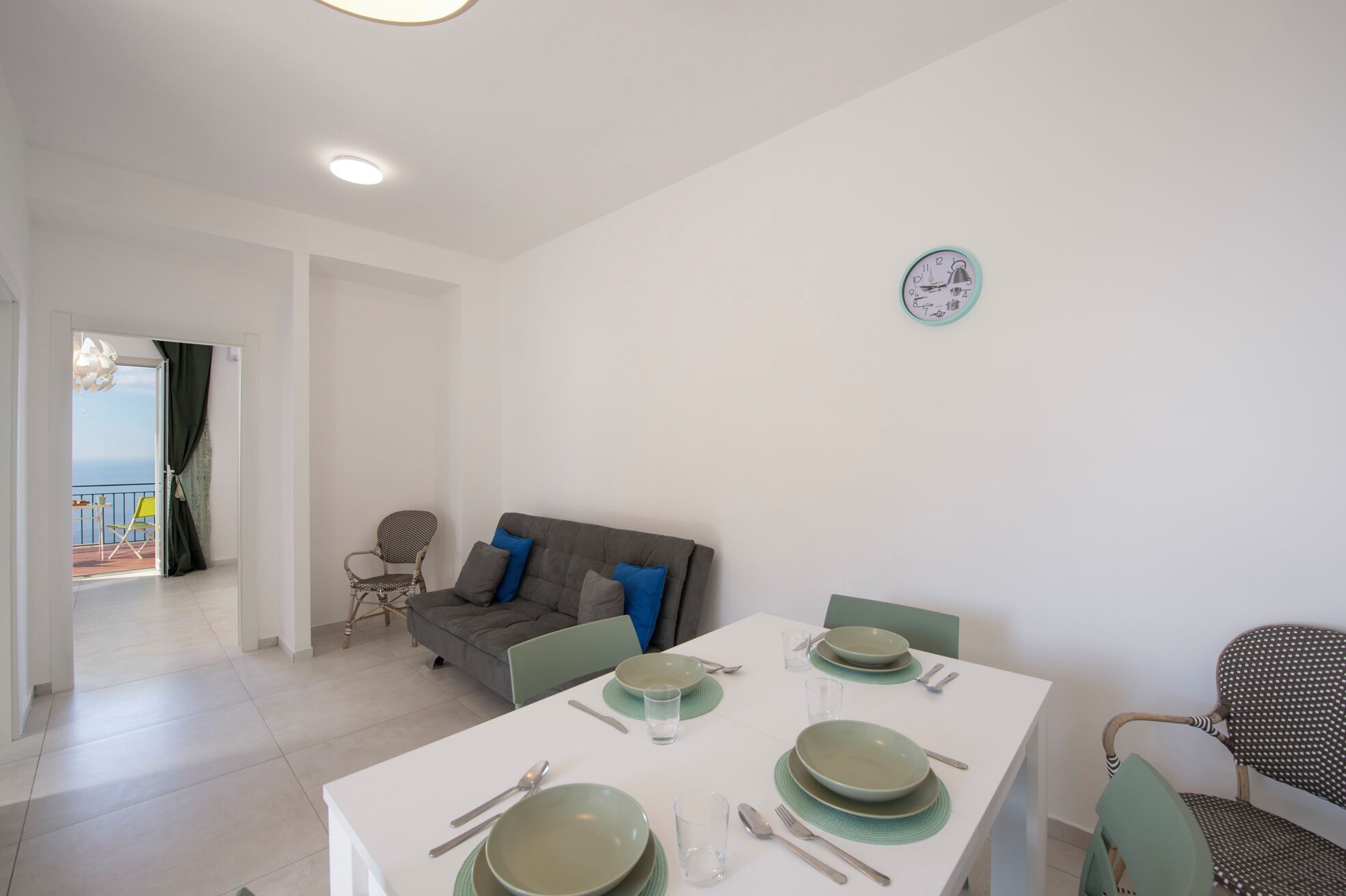 Un coin repas avec une table dressée pour quatre personnes, un canapé et un fauteuil.