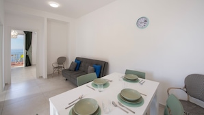 A dining area with a table set for four, a sofa, and a chair. - VivimiHome - Casa Angelina (Conca dei Marini)