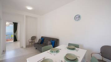 Un coin repas avec une table dressée pour quatre personnes, un canapé et un fauteuil.