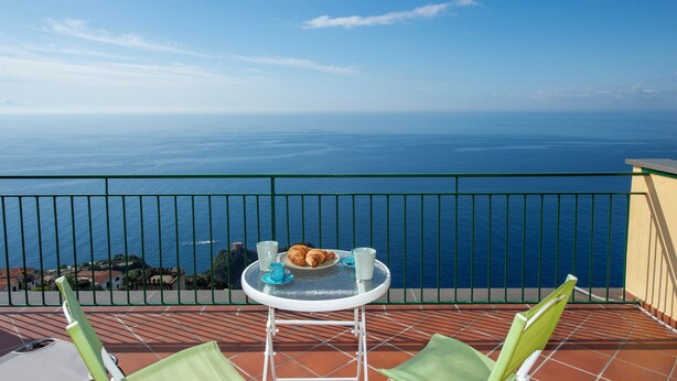 A balcony with a table set for two, overlooking a vast ocean. - VivimiHome - Casa Angelina (Conca dei Marini)
