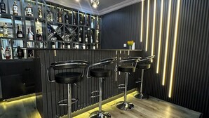Eine Bar mit Holzboden, drei Barhocker, einer Flaschenregal und einem modernen Deckenstil.