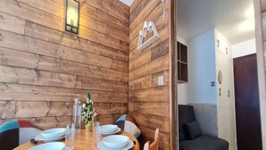 Un comedor con una pared de madera, una mesa con platos, vasos y cubiertos, y un pequeño árbol de Navidad.