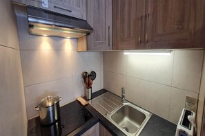 A modern kitchen with a stainless steel stove, a sink, and wooden cabinets. - Mountain Home, Balcony & Ski Access (Les Deux Alpes)
