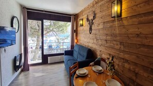 Un rincón comedor acogedor con una pared de madera, un sofá azul y una mesa dispuesta para dos.
