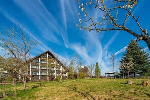 A hotel with a traditional wooden facade, a large open lawn, and a clear blue sky. - Hotel Heiderhof by Belvilla- Double Room (Obersteinebach)