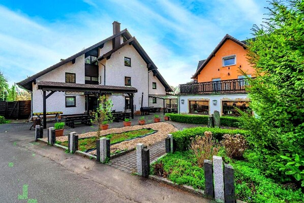 A traditional chalet-style building with a covered patio area and a garden. - Hotel Heiderhof by Belvilla- Double Room (Obersteinebach)