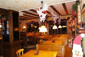 A restaurant interior with wooden tables and benches, festive decorations, and warm lighting. - Hotel Heiderhof by Belvilla- Double Room (Obersteinebach)